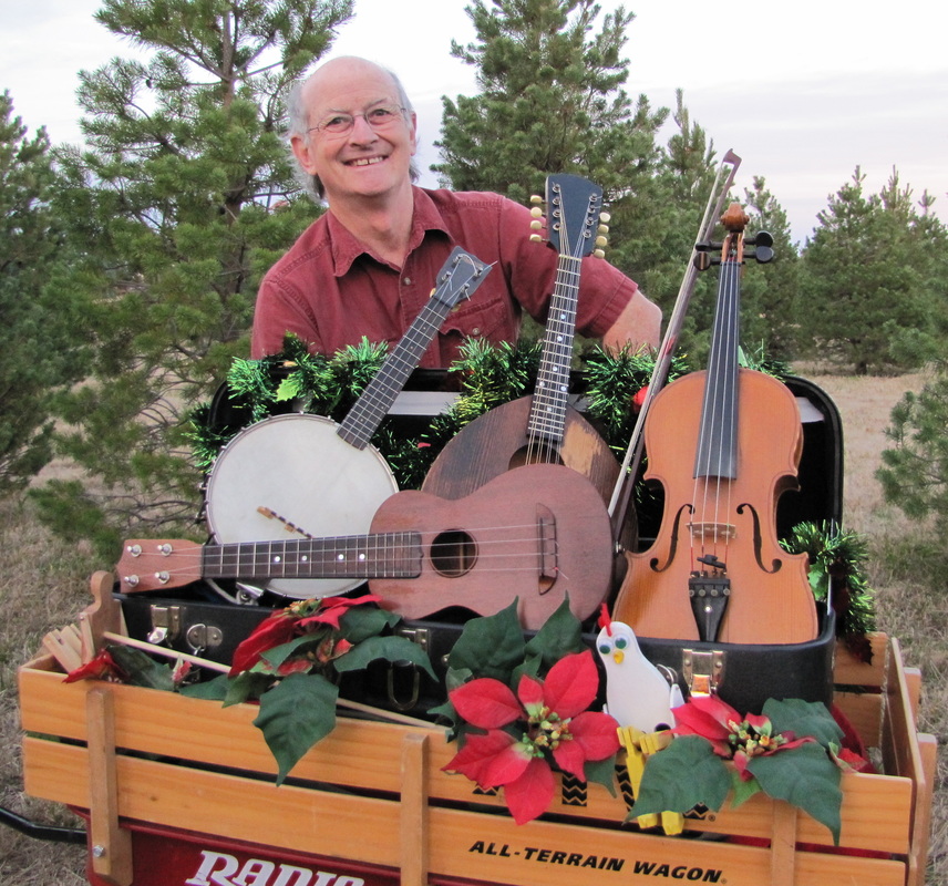 Thad Beach with fiddle, mandolin, bando uke, ukulele and chicken limberjack in a wagon with Christmas decor